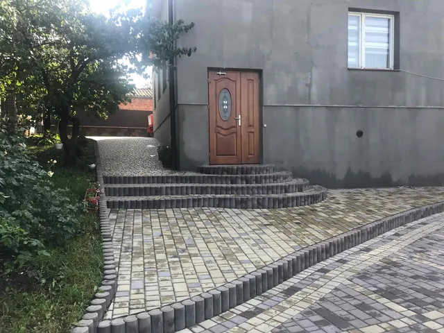 Вхід до будинку: сходи з бордюрів і бруківка